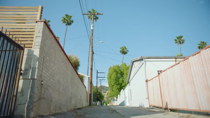 Wooden and brick fences block the sides of an alley through a neighborhood