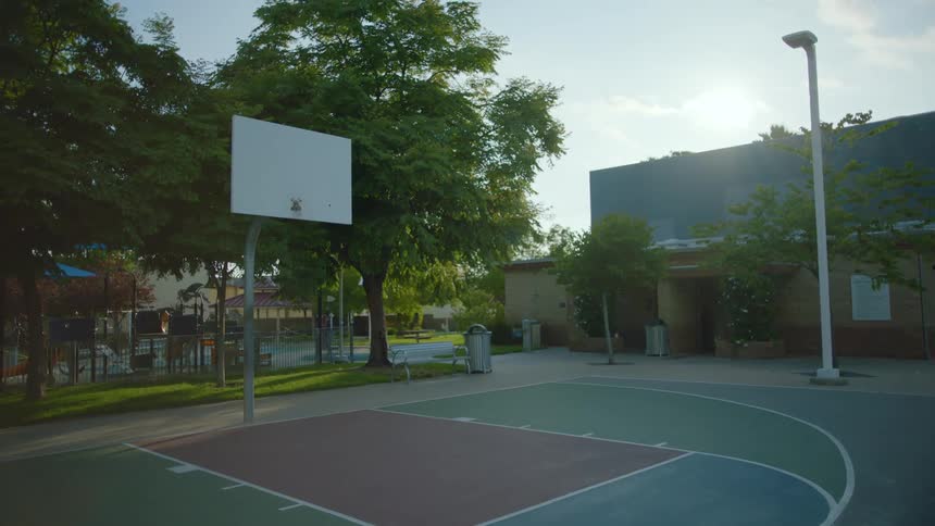 A shot of a park with a basketball court