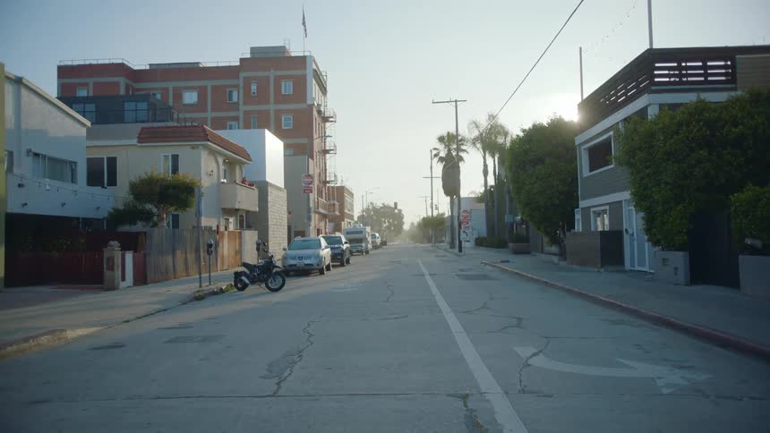 Vehicles sit parked along the side of a street in the city