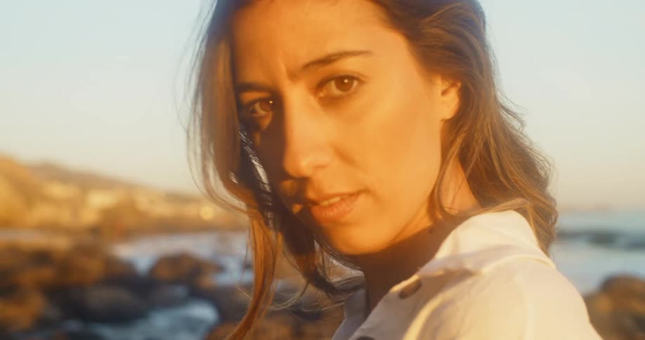 A woman standing outdoors at the coast poses for the camera