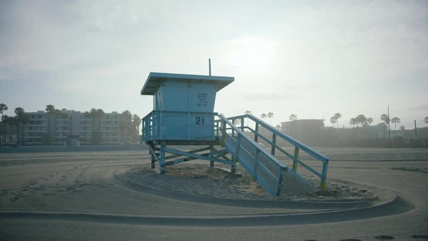 Close up of a lifeguard station on a beach with a person biking in the background