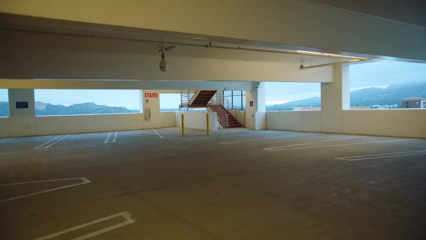 The interior of a parking structure contains multiple empty spaces and a set of stairs