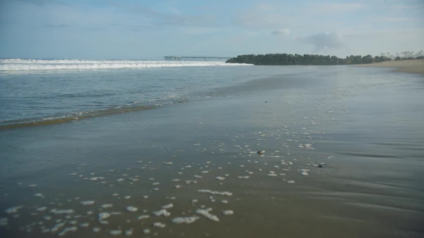 A beach with sand with the ocean sky and clouds in the background