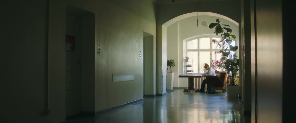 A person is sitting in a room at a table at midday