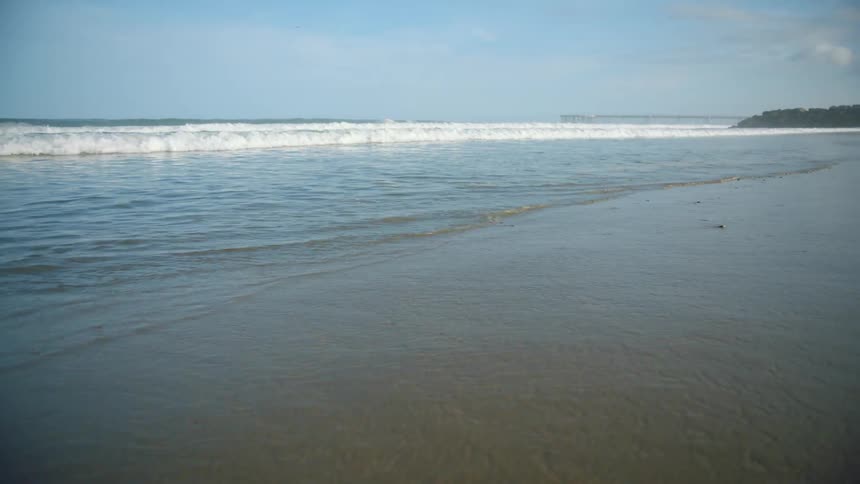 A beach with sand with the ocean sky and clouds in the background