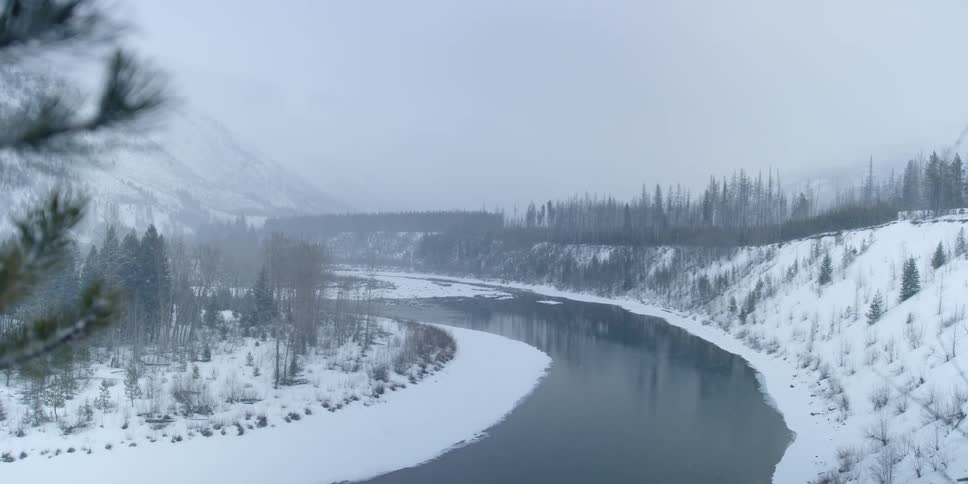 A view of a snow storm over a river in the forest