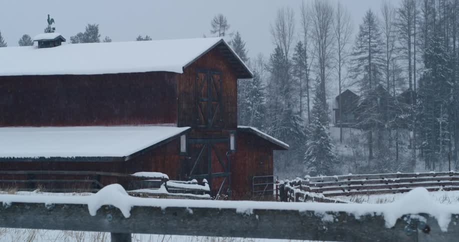 A cabin covered in snow with trees the sky and clouds in the background