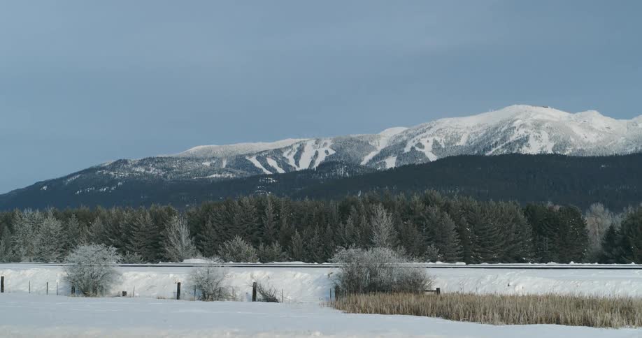 Snow covered grassland with mountains and slopes behind