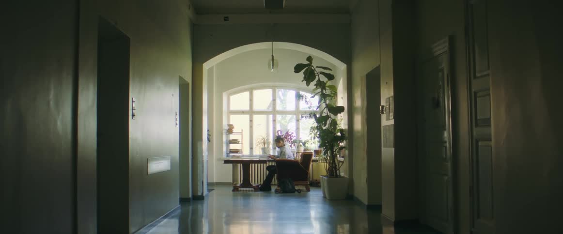 A person reads a book while sitting at a desk indoors during the day