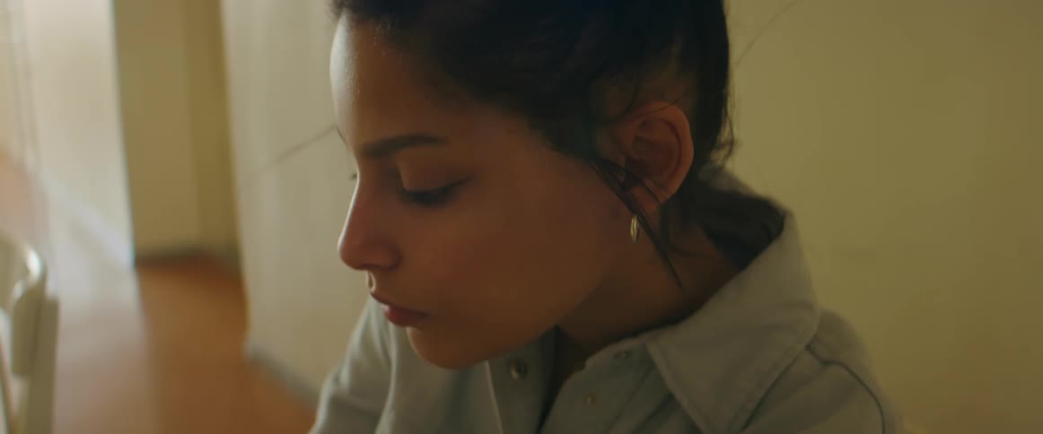 A woman sitting at a table looking down as she works