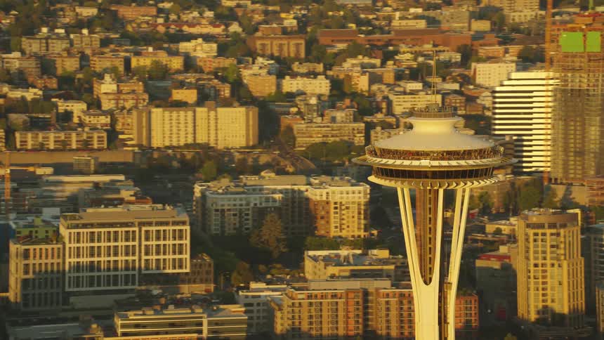 The seattle space needle stands above city buildings on a golden day