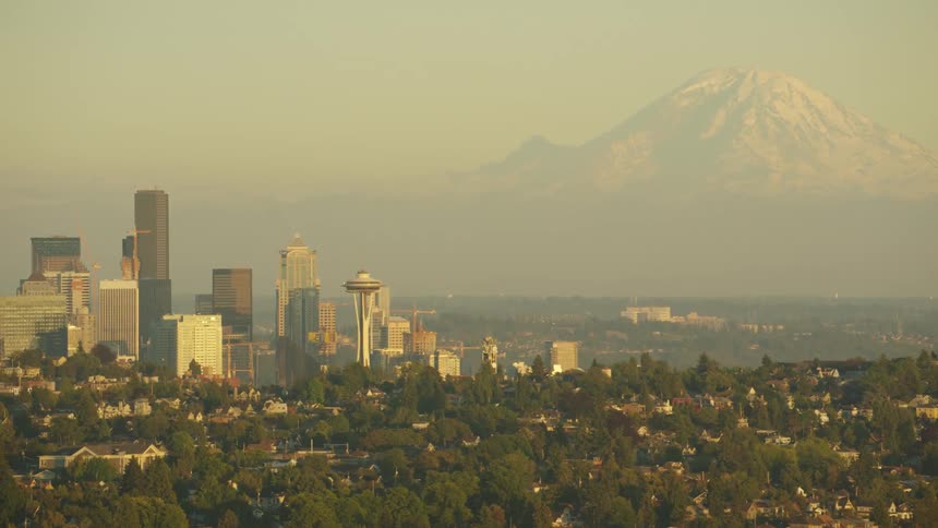 A snow capped mountain looms in the distance of a city skyline