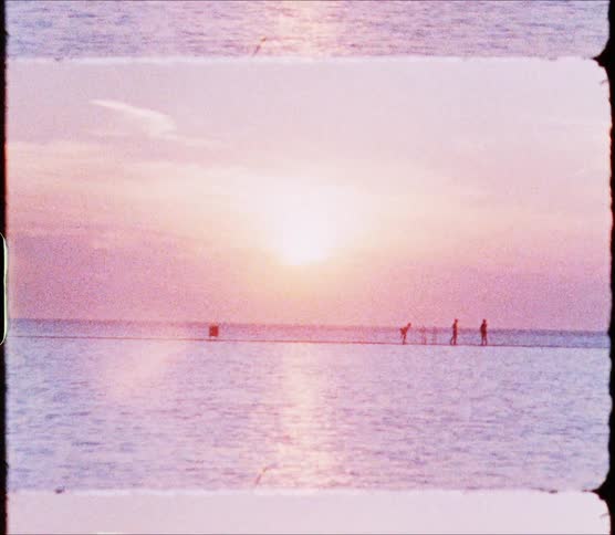 A group of people at the beach at sunset