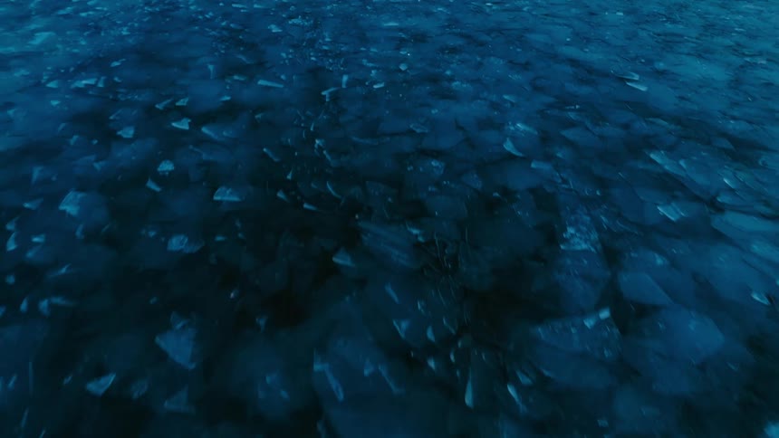 Cracked ice covers the surface of the water