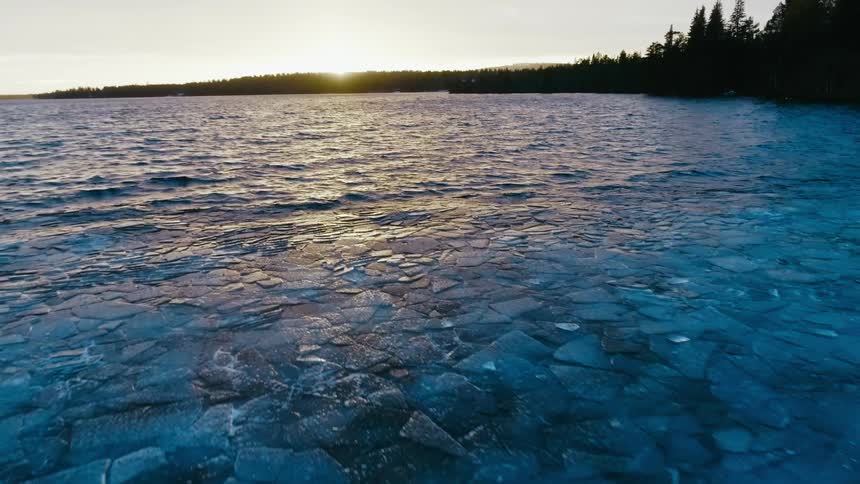 Waves roll towards shore where broken ice floats on the surface