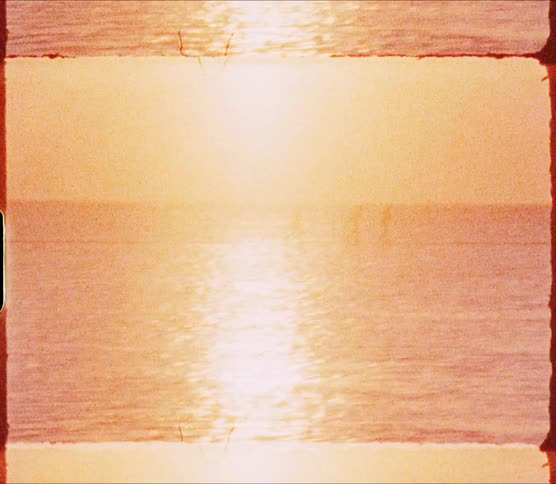 Silhouettes of three people race along walkway in middle of rippling water reflecting sun sitting in red sky