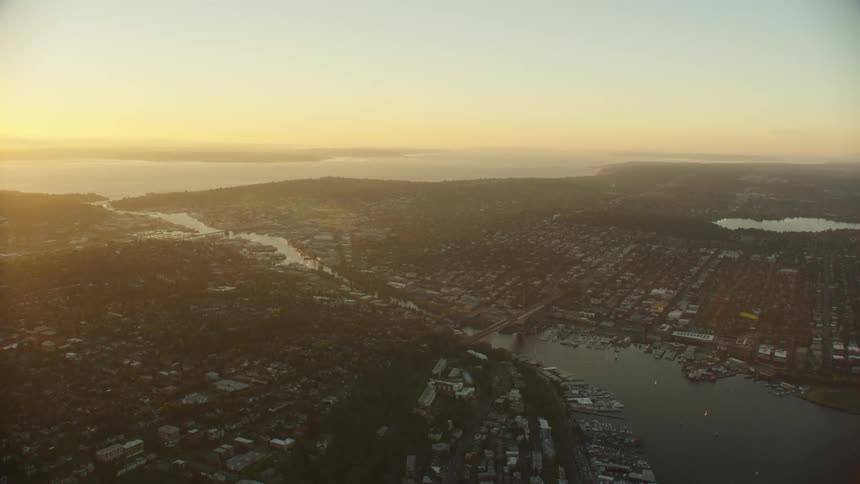 Haze obscures large town surrounding lake and red sky on horizon