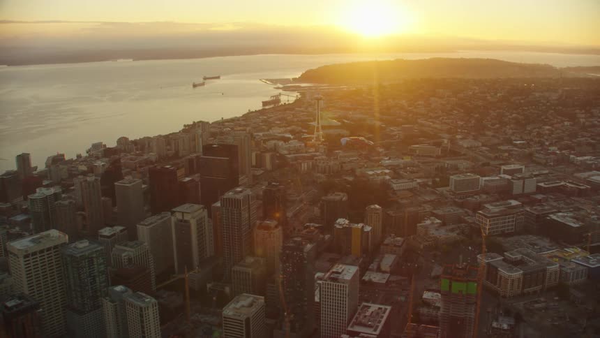 Sun shines from horizon across water toward downtown on a hazy day