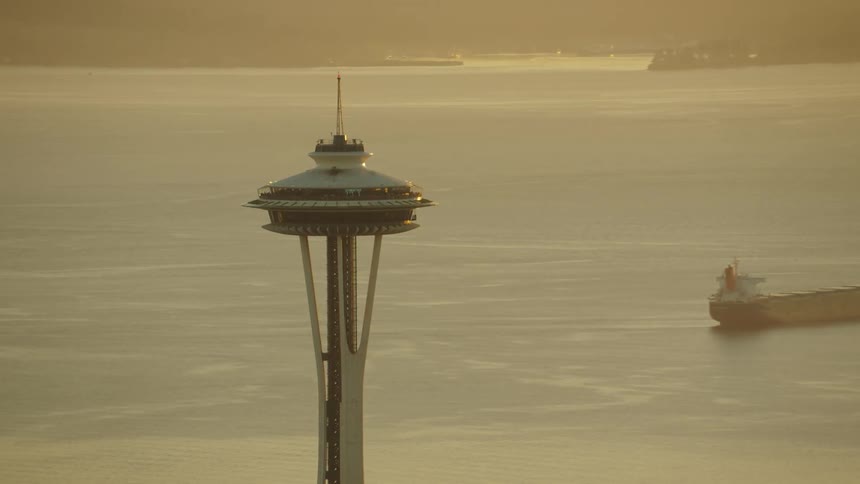 A tower needle with a body of water ships and land in the background