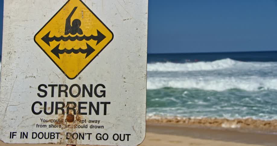 A sign on the beach warns of a strong current