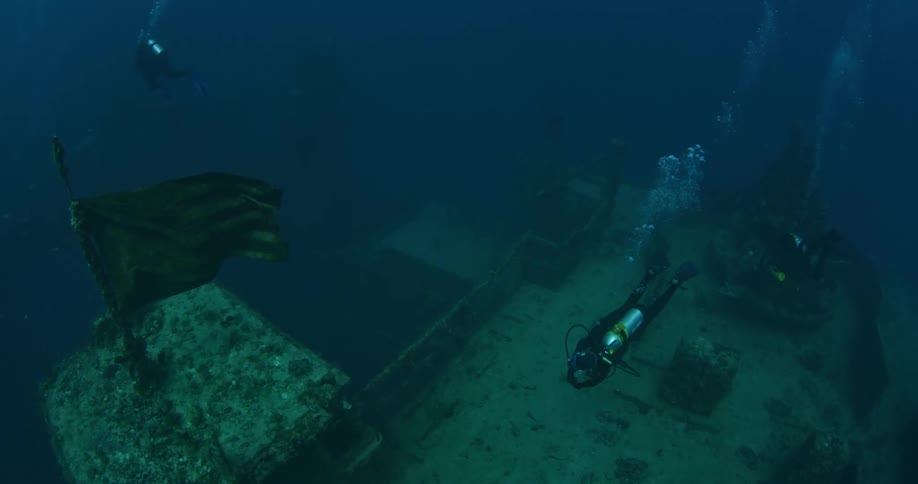 People are scuba diving in dark waters