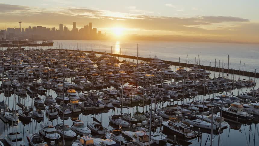 Ascending over boats docked along a city marina at sunrise
