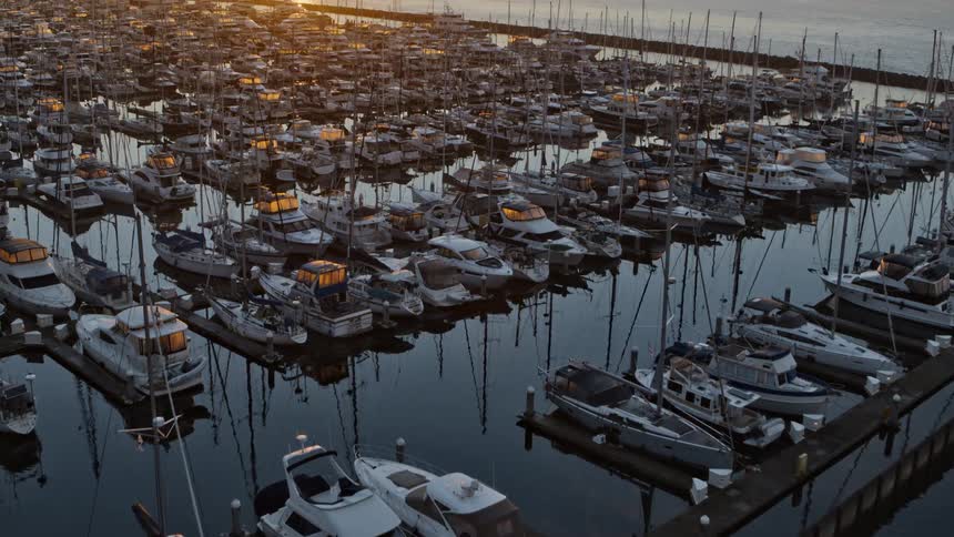 Early morning sunshine starts to illuminate boats and yatchs docked at a urban city marina