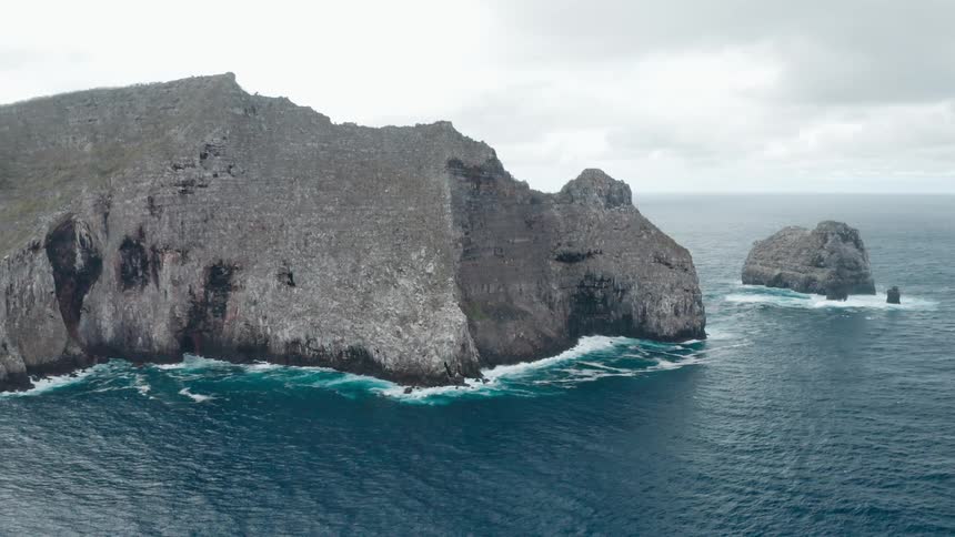 Aerial view of ocean waves crashing on the coastline of a promontory