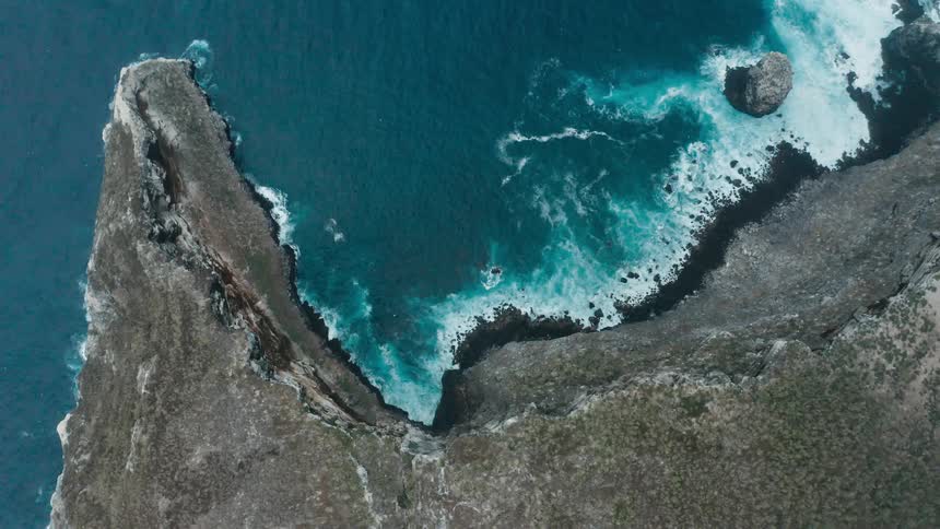 Aerial view of ocean waves crashing on the coastline of a promontory