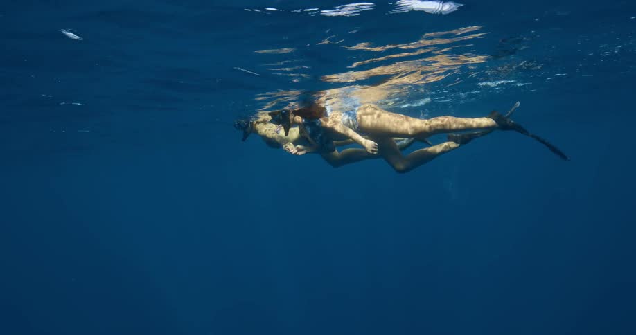 Two women with snorkels and flippers swimming underwater