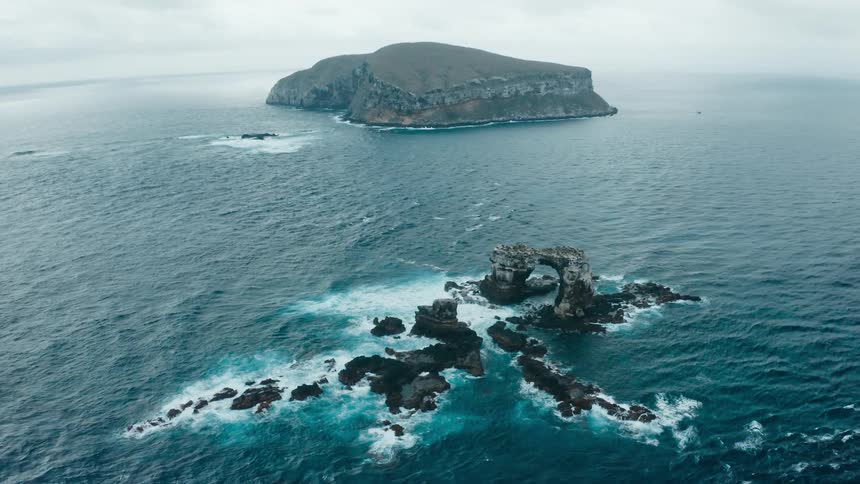 The waves crash against the rocks by the island