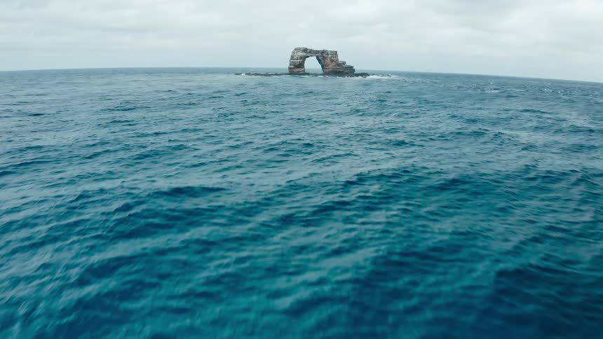 Natural arch rock formation in the ocean under a cloudy sky