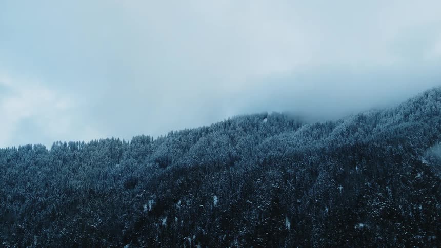 Camera shows clouds rolling over forested hills on a rather cloudy day