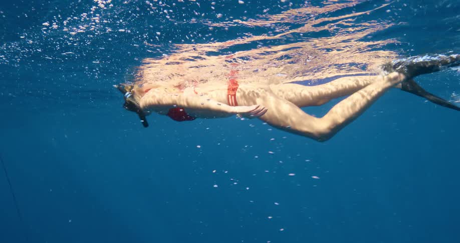 A woman is swimming in the blue waters