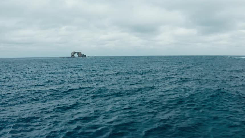 Natural arch rock formation in the ocean under a cloudy sky