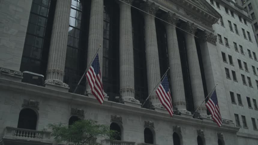 The new york stock exchange building with flags and a tree in the front