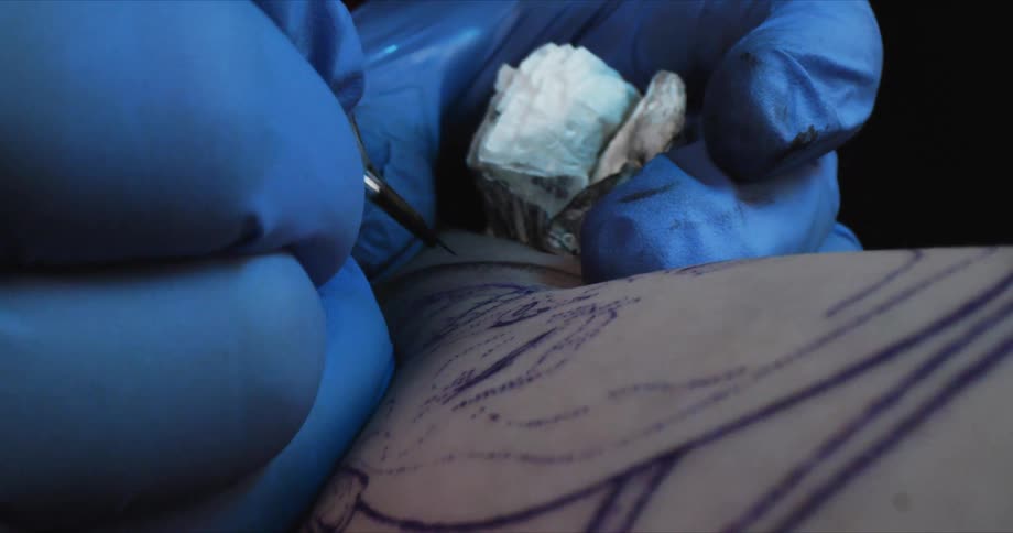 A tattoo artist creating a tattoo on a an arm