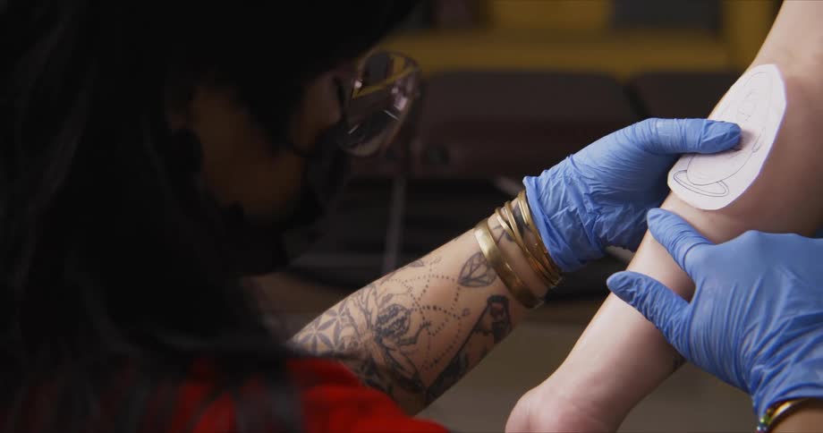 A tattoo artist examines a womans arm