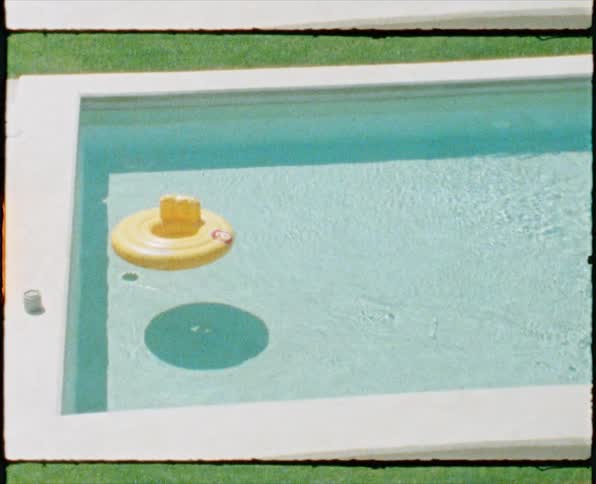 Yellow inflatable chair floating in the swimming pool caught on vintage film