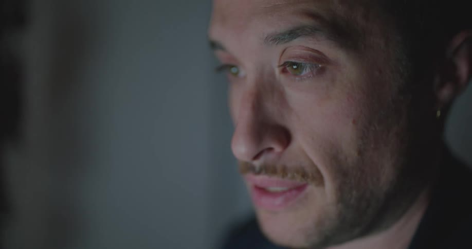 Man working hard rubs his eyes because of tablet screen light