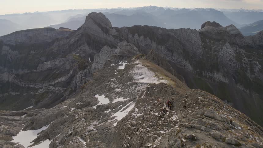 People hiking in a mountain range with ice and snow with the sky and clouds in the background