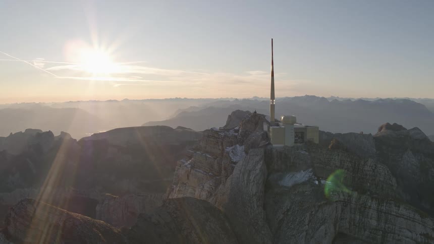 Building on top of a mountain with the sun shining brightly upon it