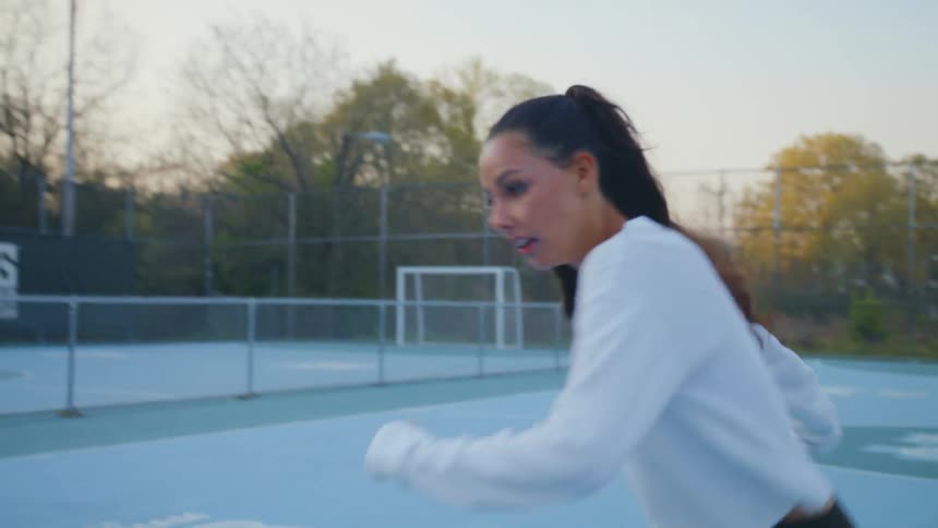 Woman runs down a soccer field turns and kicks a ball