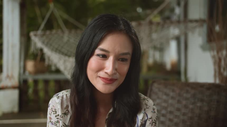 A woman is sitting outdoors in spring and smiling
