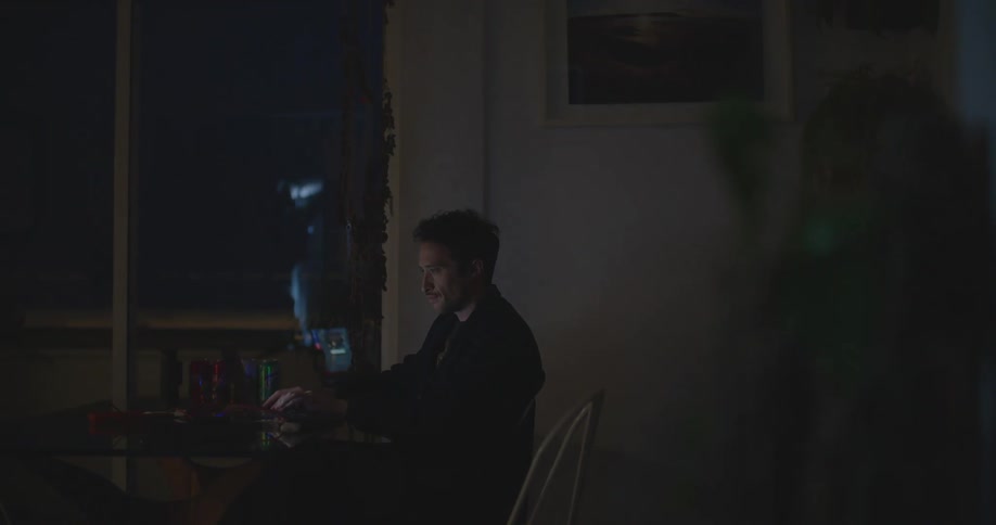 A man checks his phone and then turns his attention to his laptop