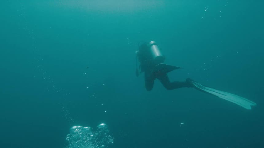 A person with scuba gear swimming underwater with bubbles