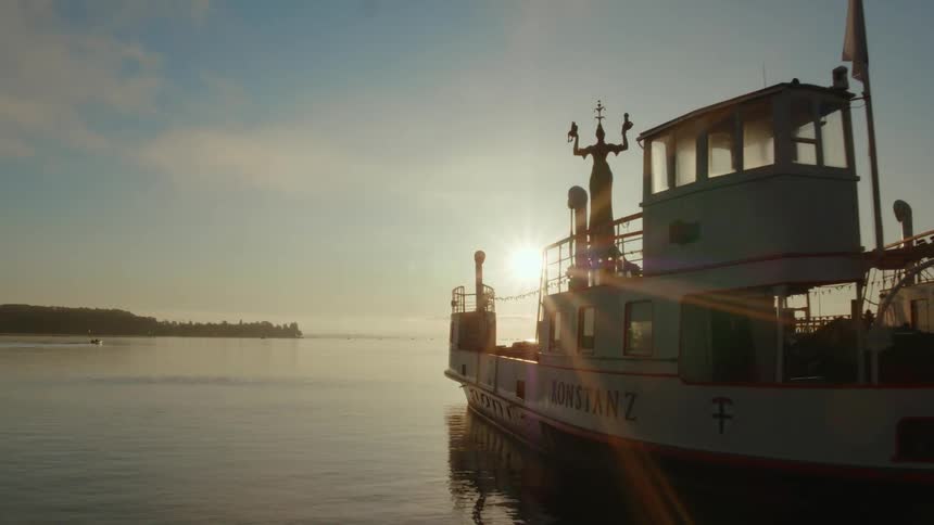 A large boat sits on a river by a port or pier