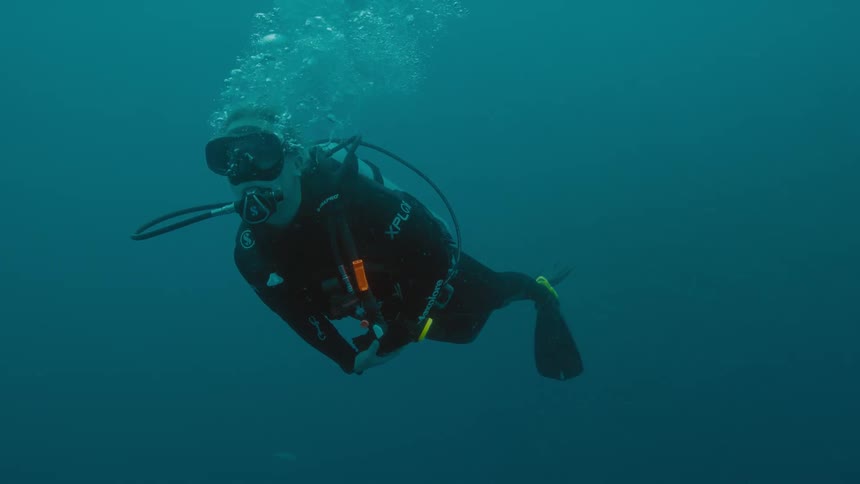 A scuba diver swims in the ocean blowing bubbles