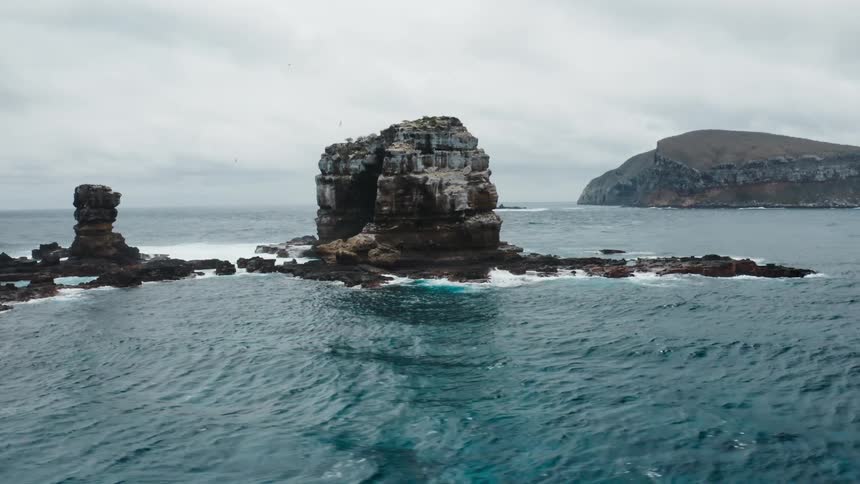 Natural arch rock formation in the ocean under a cloudy sky