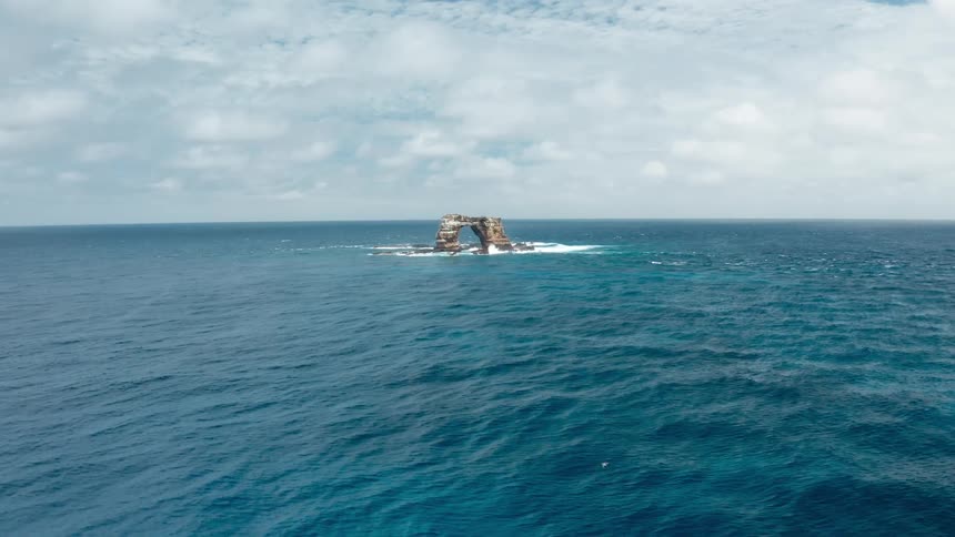 Natural arch rock formation in the ocean under a cloudy sky